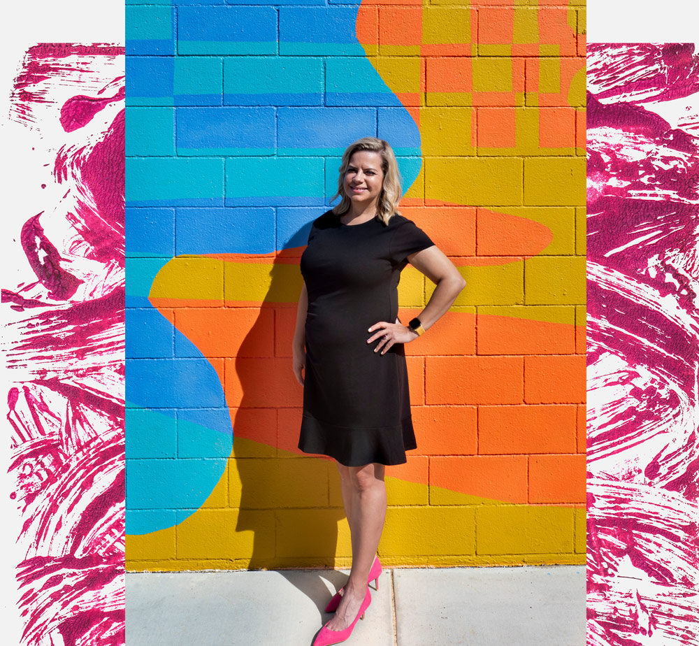 Lisa Burford stands in front of a colorful wall mural in Palm Springs, California